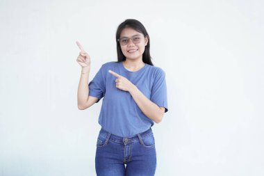 Güzel Asyalı kadın yan fotokopi alanına işaret ederken gülümsüyor, beyaz arka planda reklam veya promosyonlar için mükemmel.