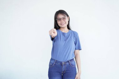 Güzel bir Asyalı kadın sana doğru bakarken sıcak bir şekilde gülümser. Beyaz bir arka plana karşı seni davet eden bir jest yapar.