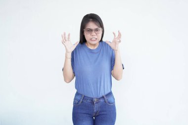 Güzel bir Asyalı kadın kızgın bir jest yapıyor, kaşları çatık ve yumrukları sıkılmış, beyaz bir arka plana karşı hayal kırıklığını ifade ediyor.