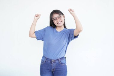 Güzel Asyalı kadın parlak bir gülümseme sergiliyor, yumruklarını kaldırıyor muzaffer bir 'evet' zafer jesti beyaz arka plana karşı