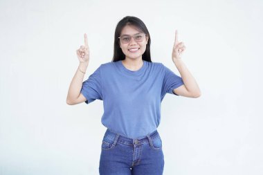 Güzel bir Asyalı kadın, beyaz bir arka planda izole edilmiş reklamcılık ya da promosyon konseptini öne sürerek, ilginç bir ifadeyle yukarı bakar ve işaret eder.