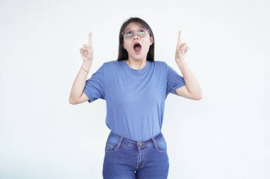 Güzel bir Asyalı kadın, beyaz bir arka planda izole edilmiş reklamcılık ya da promosyon konseptini öne sürerek, ilginç bir ifadeyle yukarı bakar ve işaret eder.