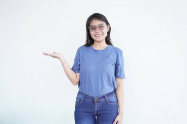 Güzel Asyalı kadın, beyaz bir arka planda açık avucunda bir ürünü sunarken gülümsüyor.