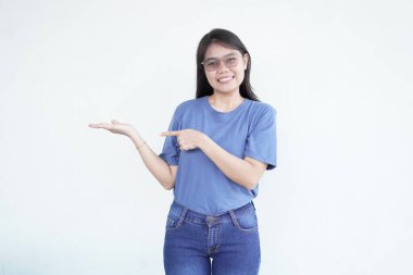 Güzel Asyalı kadın, beyaz bir arka planda açık avucunda bir ürünü sunarken gülümsüyor.