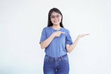 Güzel Asyalı kadın, beyaz bir arka planda açık avucunda bir ürünü sunarken gülümsüyor.