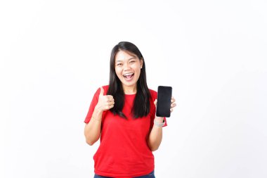 Güzel bir Asyalı kadın beyaz arka plana karşı boş ekranlı akıllı bir telefonu tutarken başparmağını kaldırıyor.