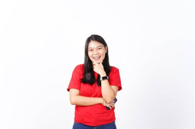 Güzel Asyalı kadın kollarını kavuşturup beyaz bir arka plana yaslanmış kendine güvenen bir poz veriyor.