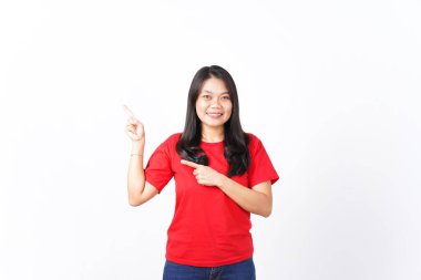 Gülümseyen, sunan ve işaret eden, beyaz arka planda izole edilmiş kırmızı tişörtlü, güzel Asyalı kadının reklamını yaptığı için.