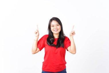 Gülümseyen ve işaret eden kırmızı tişörtlü güzel Asyalı kadın beyaz arka planda izole edilmiş