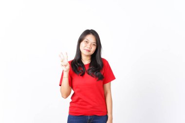 Gülümseyen ve parmaklarını gösteren, Güzel Asyalı Kadın 'ın Üç Parmağı, beyaz arka planda kırmızı giyinmiş.