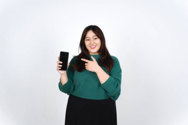 Beyaz arka planda izole edilmiş yeşil giyinen güzel Asyalı Kadın 'ın reklam ya da uygulamaları için boş ekran akıllı telefonunu sunarak ve tutarak gülümsüyor