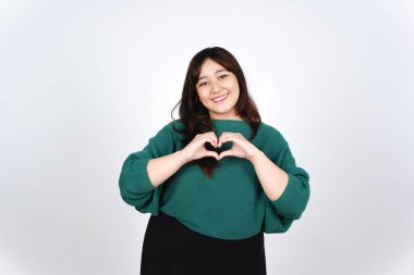 Beyaz arka planda yeşil giyinmiş güzel Asyalı kadının el işaretini göster ve sevgini göster.