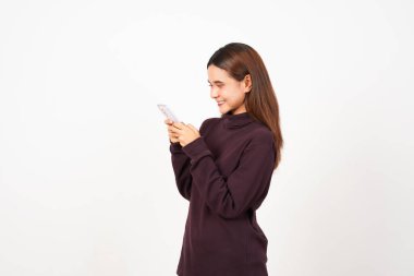 Beyaz arka planda izole edilmiş güzel bir Asyalı kadının akıllı telefonunu kullanırken gülümsüyordu.