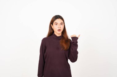 Beyaz arka planda tecrit edilmiş güzel bir Asyalı kadının baş parmağıyla işaret eden yüz ifadesi.