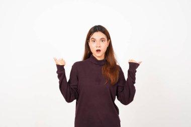 Gülümseyen ve işaret eden beyaz arka planda izole edilmiş güzel bir Asyalı kadının başparmağıyla