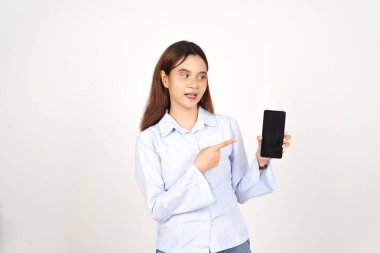 Beyaz arka planda izole edilmiş Asyalı güzel bir kadının akıllı telefonuna şaşırmış ve işaret ediyor.