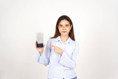 Beyaz arka planda izole edilmiş güzel Asyalı kadının akıllı telefonuna gülümseyen ve işaret eden.