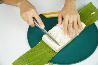Kadın elleri kesme tahtasındaki Tempeh bloğunu dilimliyor