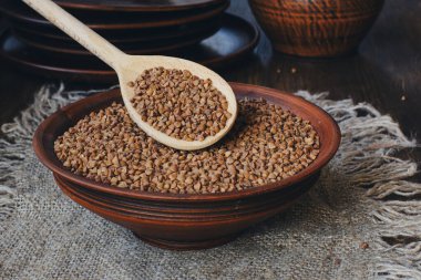 Köy tabaklarında çiğ karabuğday ve ahşap kaşık. Yan görünüm.