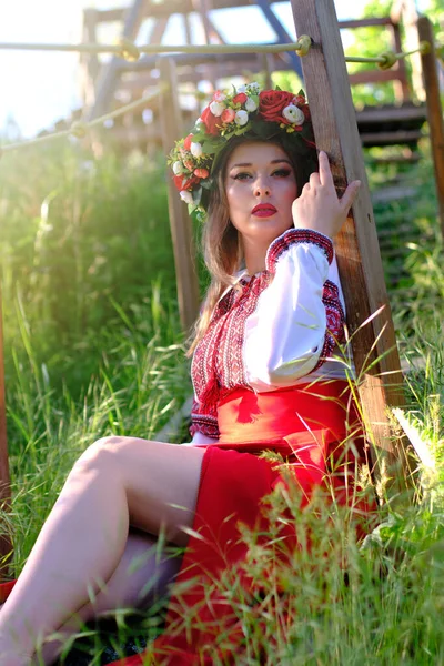 ウクライナの民族衣装で公園の草の上に座っている少女 — ストック写真