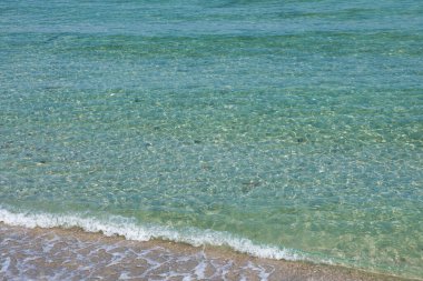 Kıyıda ışık dalgaları olan berrak deniz suyu. Parça.