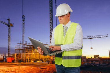 İnşaat alanının arka planında dizüstü bilgisayarı olan ustabaşı.