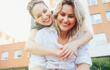 İki neşeli kız aşağı bakıyor ve yaz kıyafetleri içinde gülümsüyor. Alt manzara, yakın plan.