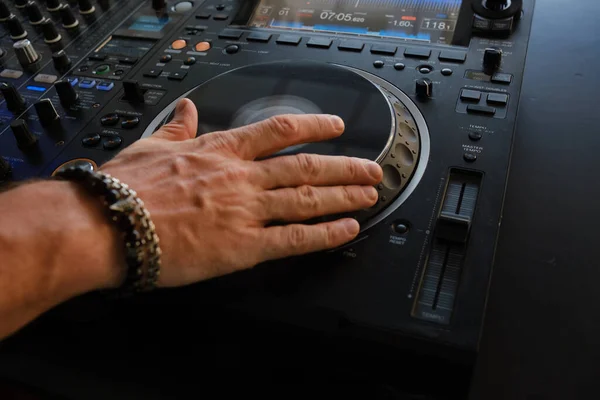 DJ\'s hand on the mixing console, close-up. Fragment.