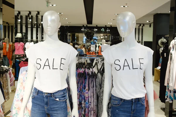Two mannequins in white t-shirts and jeans with the words 
