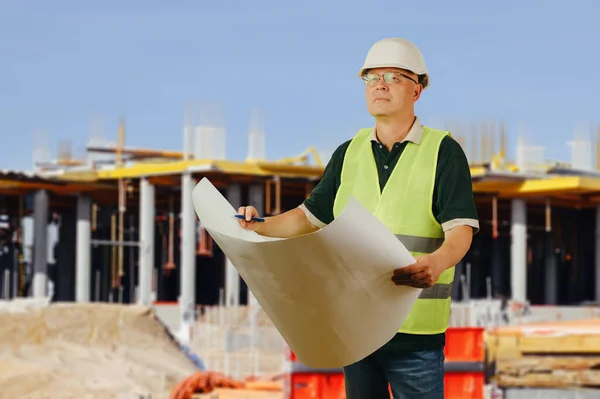 Foreman with a paper drawing on the background of a construction site