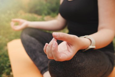 Yakından bakınca, eller lotus pozisyonunda meditasyon yapar. Akıllı saati olan bir kız gibi. Seçici odak.