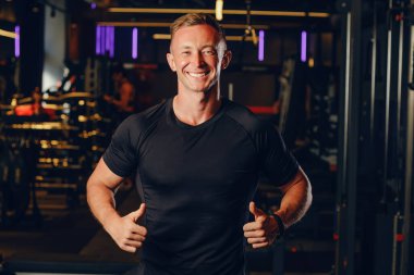 Siyah tişörtsüz atlet adam baş parmak işareti yapıyor ve kameraya gülümsüyor. Metin ya da tasarım için yer, maket, kopyalama alanı.