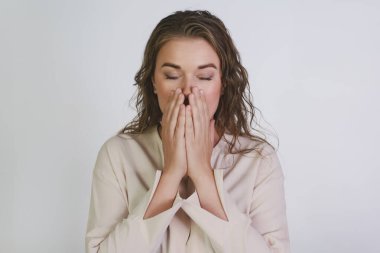 Soğuk algınlığı veya alerjisi olan bir kız avuçlarıyla ağzını kapatır, hapşırmak üzeredir..