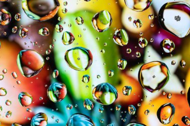 Renkli arka planda bardağa su damlatılıyor..