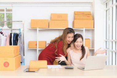 İki neşeli bayan iş ortağı, laptopta gördükleri olumlu bir tepkiye, açık ağızlı bir heyecanla tepki veriyorlar..