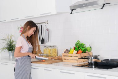 Aktif Asyalı güzel kadın mutfağında havuç soyarken görülüyor. Sahne, sağlıklı beslenmeye ve sağlıklı yaşam tarzına adanmışlığı gösteriyor..
