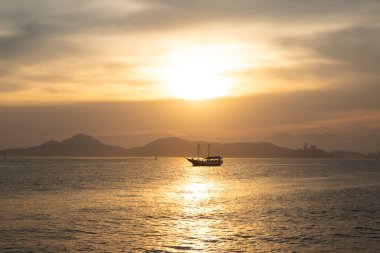 Brezilya 'nın Santos körfezinde gün batımında turistlerle yelkenli gezisi..