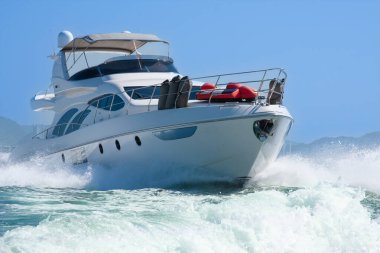 Lüks bir yat denizde yüksek hızda yüzüyor, su sıçrıyor ve açık mavi gökyüzü var. Boş zaman, macera, seyahat, özgürlük ve yaşam tarzı kavramı.