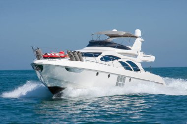 Lüks bir yat denizde yüksek hızda yüzüyor, su sıçrıyor ve açık mavi gökyüzü var. Boş zaman, macera, seyahat, özgürlük ve yaşam tarzı kavramı.