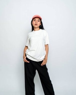 Beyaz gömlekli, şapkalı, beyaz arka planda poz veren genç bir kadın.