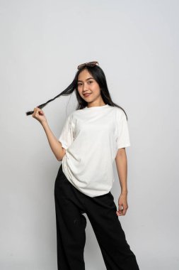 Beyaz gömlekli ve gözlüklü genç bir kadın beyaz arka planda mutlu bir poz veriyor.