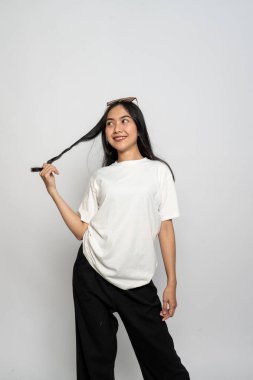 Beyaz gömlekli ve gözlüklü genç bir kadın beyaz arka planda mutlu bir poz veriyor.