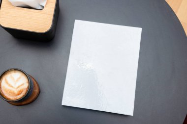 Siyah bir masanın üstündeki boş bir beyaz cilt kapağı resmi.