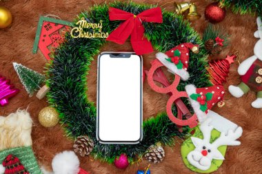 Noel süslemeleri ile birlikte boş beyaz ekran ukala görüntüsü. Noel süsleri ve renkli hediye süslemeleriyle çevrili boş bir akıllı ekran. Doldurulacak boşluk