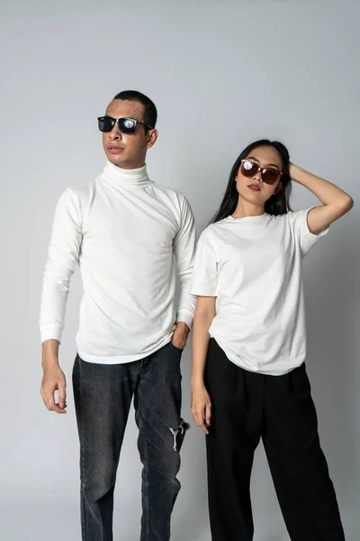 A couple wearing white blank shirt and a glasses doing a cool pose a white background