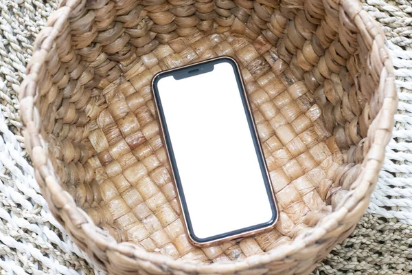 Bir sepetin üzerine yerleştirilmiş bir akıllı telefon. Model için boş beyaz resim.