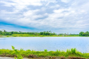 Bir sürü ağacın olduğu bir manzara, ıssız bir pavyon, bir göl, ve mavi renkli gökyüzü, görünür bir bulut, renkli bir manzara.