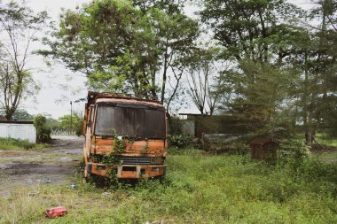 Yaralı eski bir kamyonun ön görüntüsü. Bir parkın ortasında terk edilmiş.