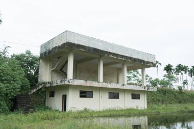 Eski terk edilmiş iki katlı bitmemiş bir bina, parkın yanında bir gölet inşa edilmiş.
