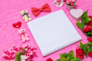 Sevgililer günü temalı dekorasyonlarla çevrili yumuşak pembe bir halının üzerinde beyaz boş bir havlu.